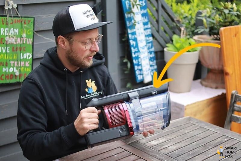 Man sieht den Knopf zum Öffnen des Schmutzbehälters.